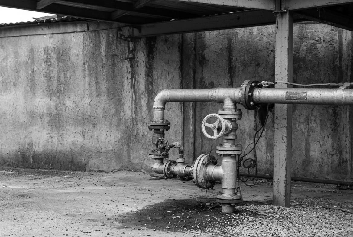 Pipework with hand-operated valves and flanged joints under a canopy.