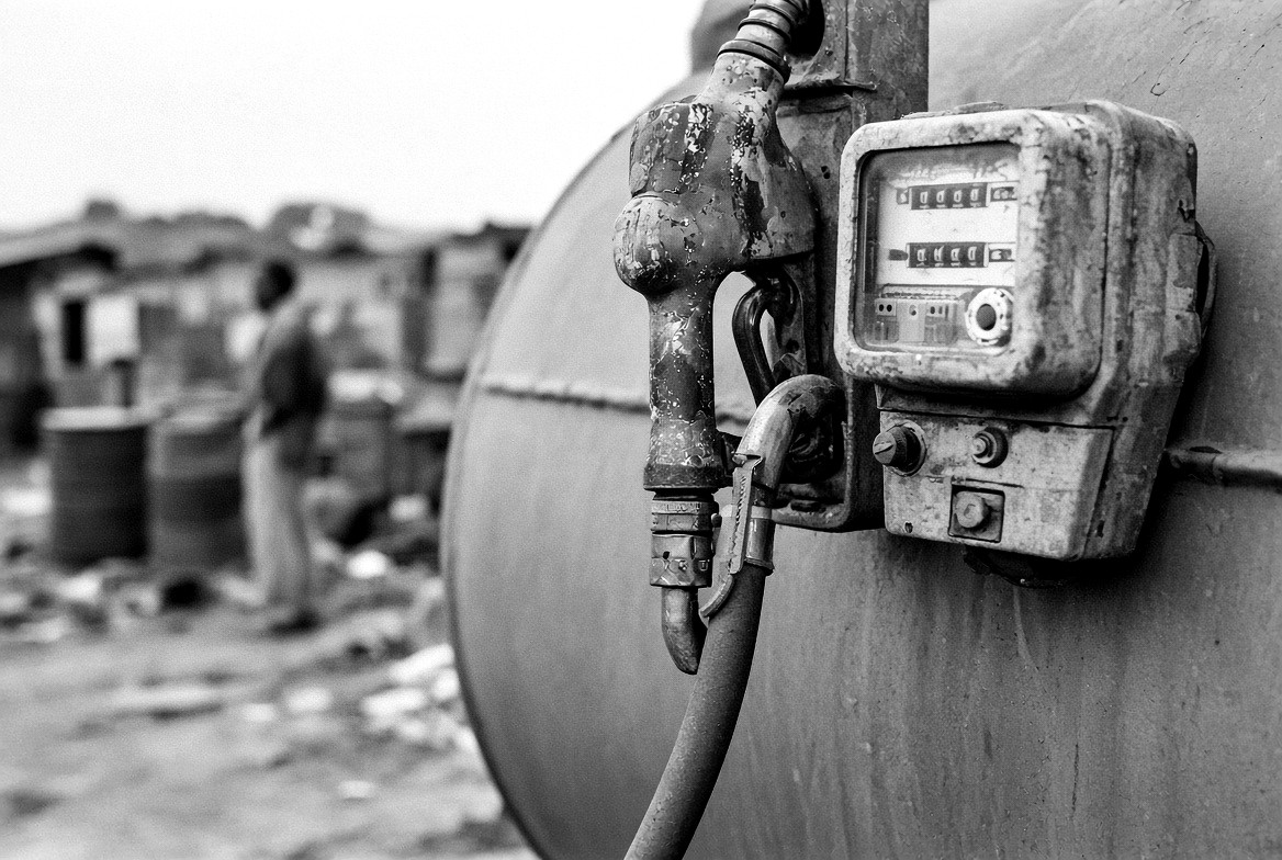 Close-up of a dispensing nozzle and a mechanical meter mounted on the side of a tank.